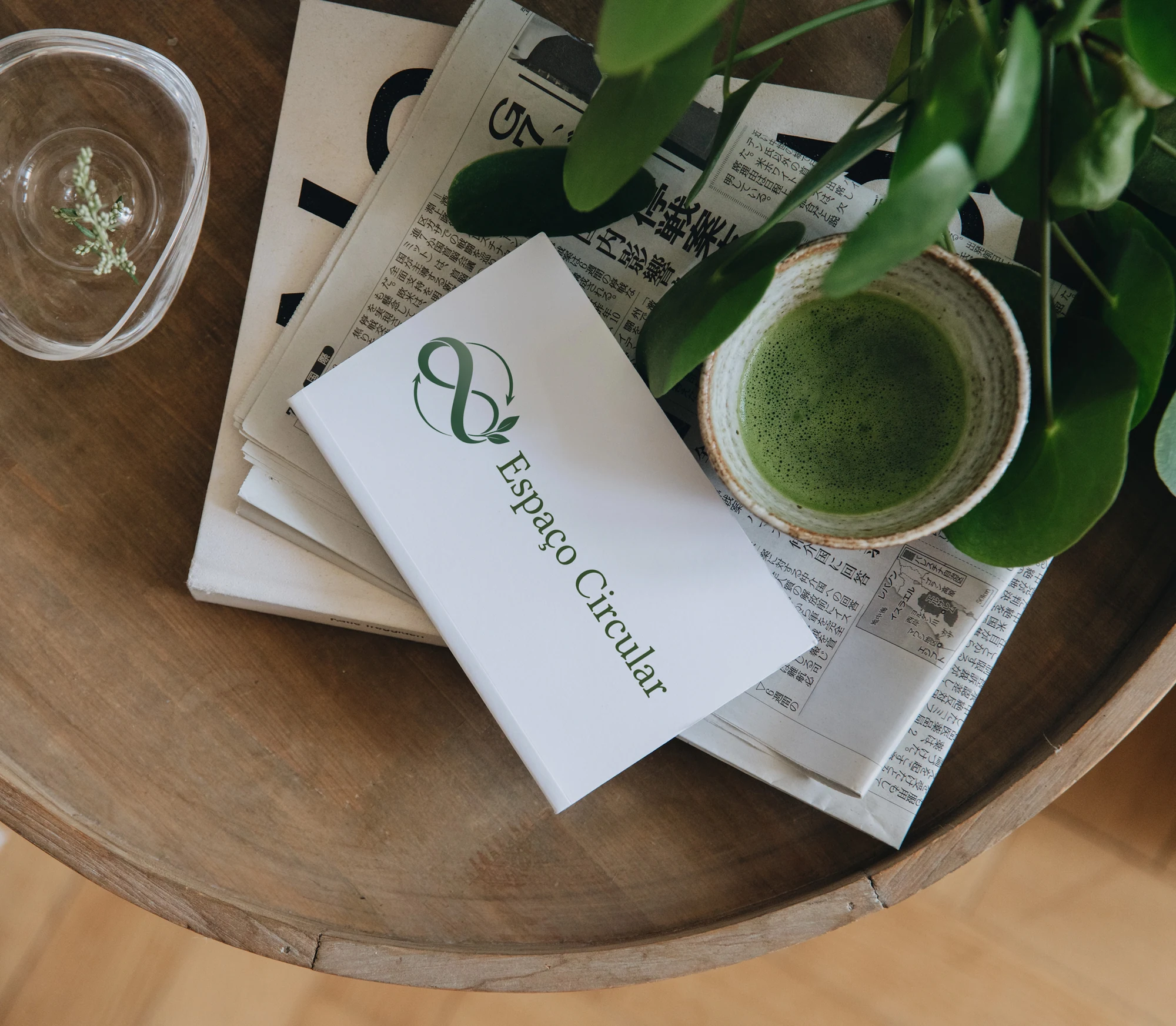 Espaço Circular identity presented on a white card beside green leaves and a cup on a wooden table
